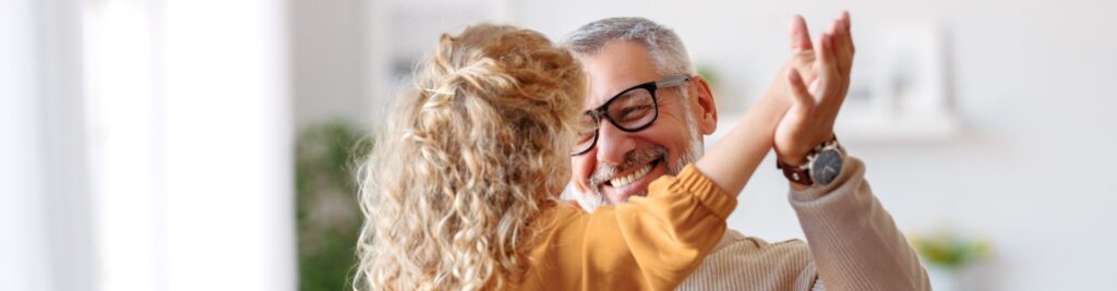 A grandfather playing with his granddaughter at home.